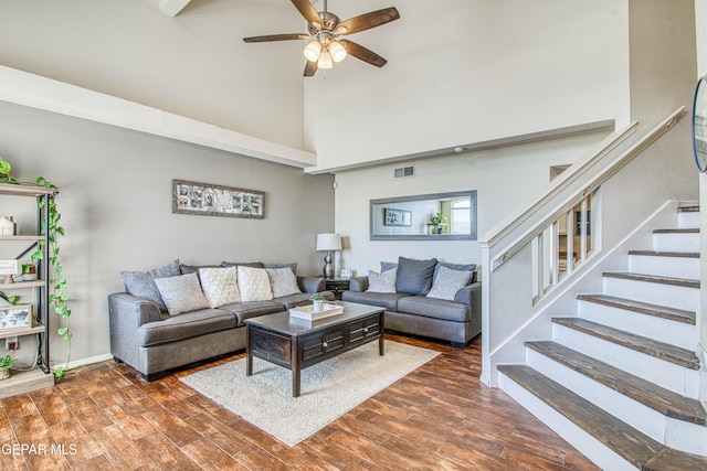 living room with ceiling fan, a high ceiling, and dark hardwood / wood-style flooring