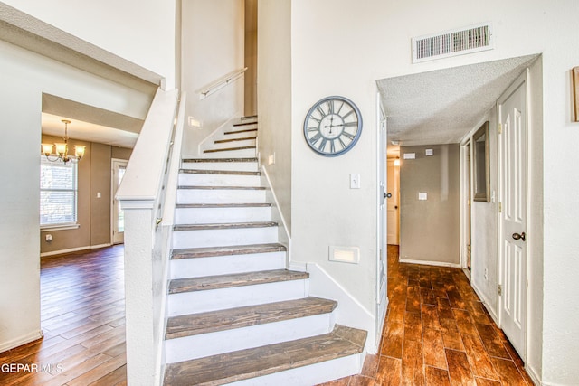 stairs with hardwood / wood-style flooring and a notable chandelier