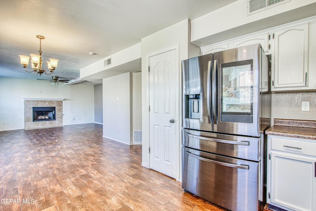 kitchen featuring a fireplace, pendant lighting, an inviting chandelier, stainless steel fridge with ice dispenser, and white cabinets