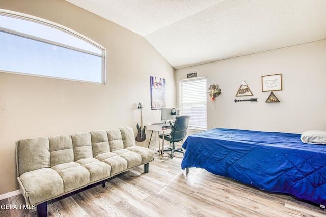 bedroom with vaulted ceiling, a textured ceiling, and wood-type flooring