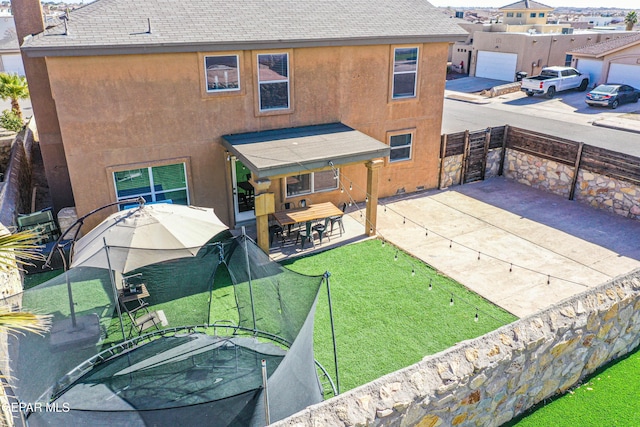 back of house with a lawn and a patio