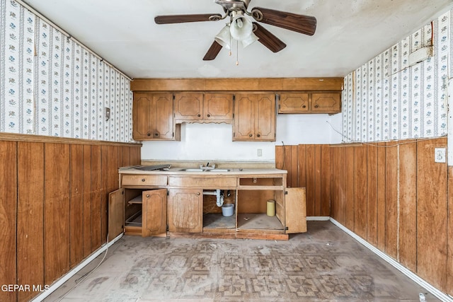 kitchen featuring ceiling fan, sink, and wood walls