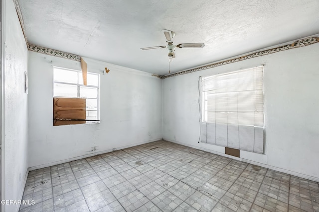 empty room with a textured ceiling, ceiling fan, and a healthy amount of sunlight