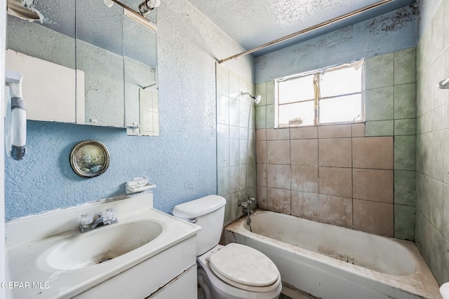 full bathroom featuring toilet, a textured ceiling, tiled shower / bath, and vanity