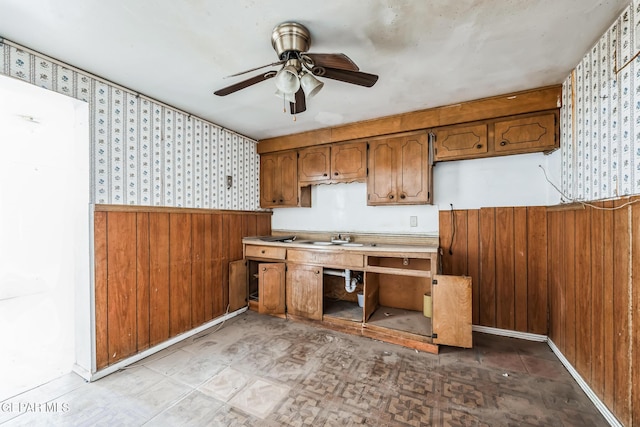 kitchen with ceiling fan, sink, and wooden walls