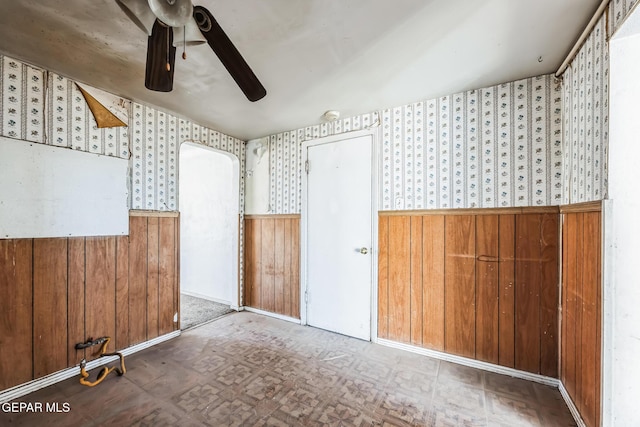 empty room with ceiling fan and wood walls