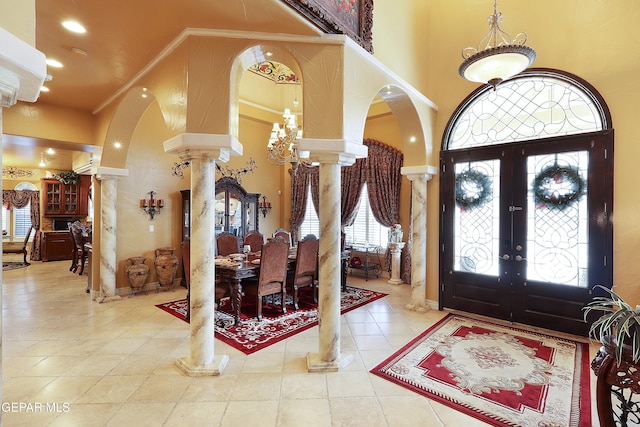 entryway featuring crown molding, tile patterned floors, ornate columns, and a high ceiling