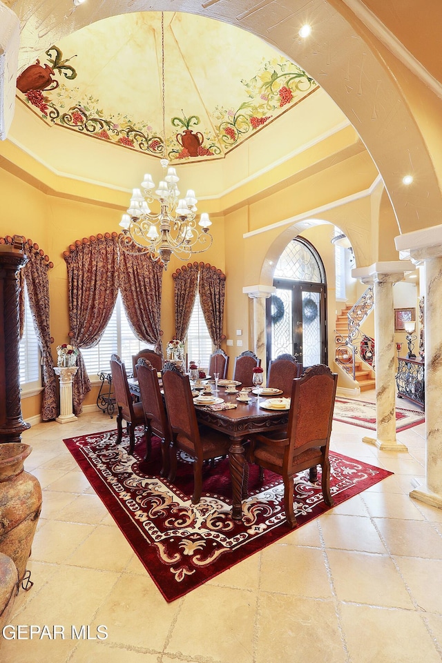 dining room featuring french doors, a chandelier, ornamental molding, decorative columns, and a high ceiling