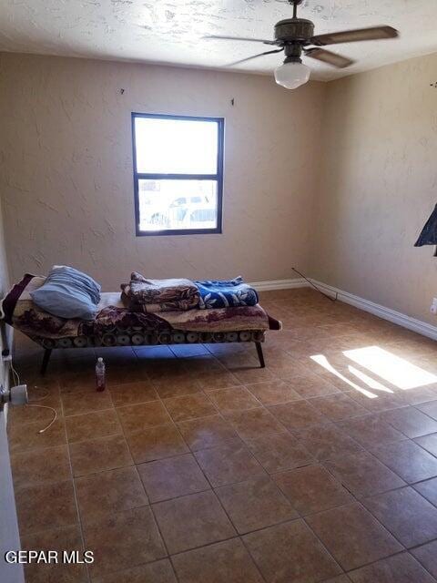 living area featuring ceiling fan and a textured ceiling