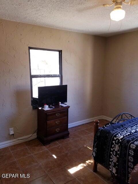 bedroom featuring dark tile patterned flooring, a textured ceiling, and ceiling fan