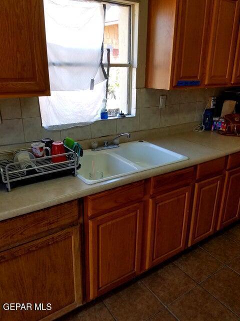 kitchen featuring dark tile patterned flooring, sink, and decorative backsplash