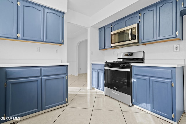 kitchen featuring light tile patterned floors, blue cabinets, and stainless steel appliances