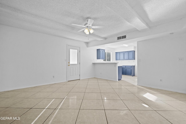 unfurnished living room with a textured ceiling, ceiling fan, light tile patterned floors, and beam ceiling