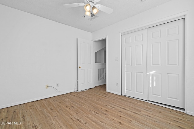 unfurnished bedroom featuring ceiling fan, light hardwood / wood-style floors, a textured ceiling, and a closet