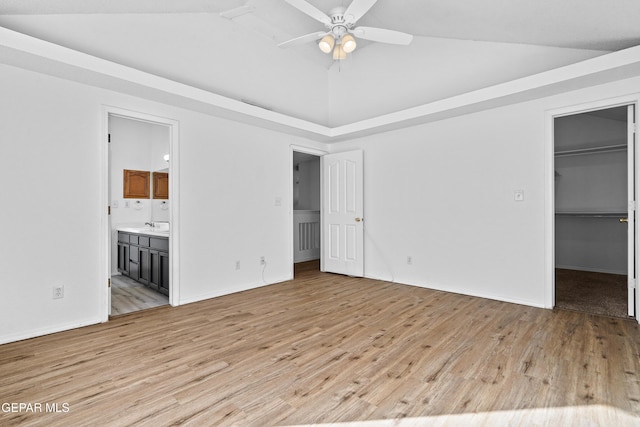 unfurnished bedroom with ceiling fan, ensuite bathroom, light hardwood / wood-style flooring, and a walk in closet