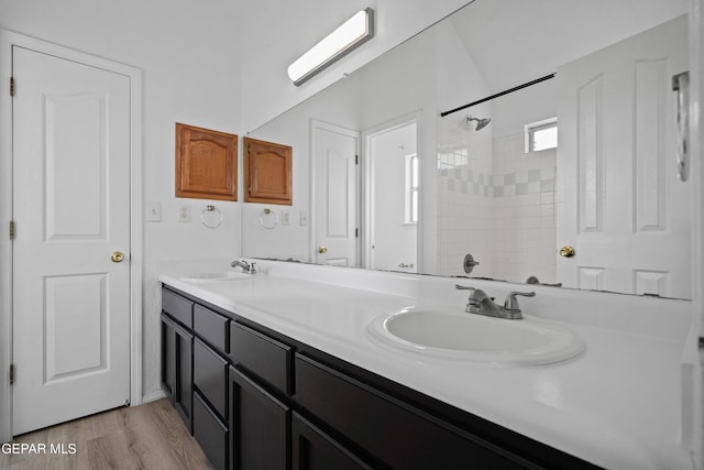 bathroom with tiled shower, wood-type flooring, and vanity