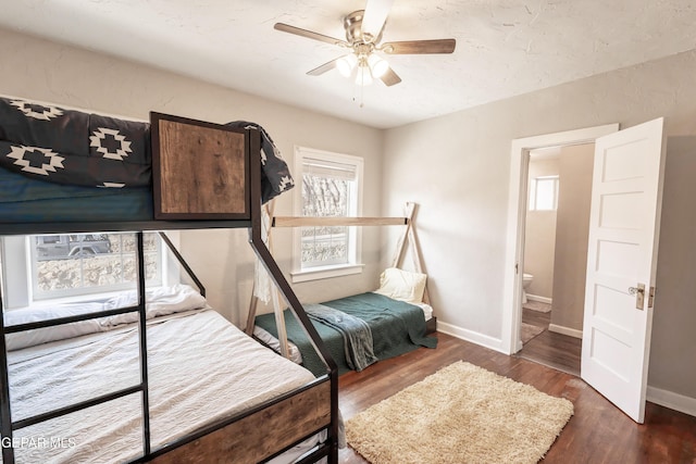 bedroom with ceiling fan, dark wood-type flooring, and ensuite bath