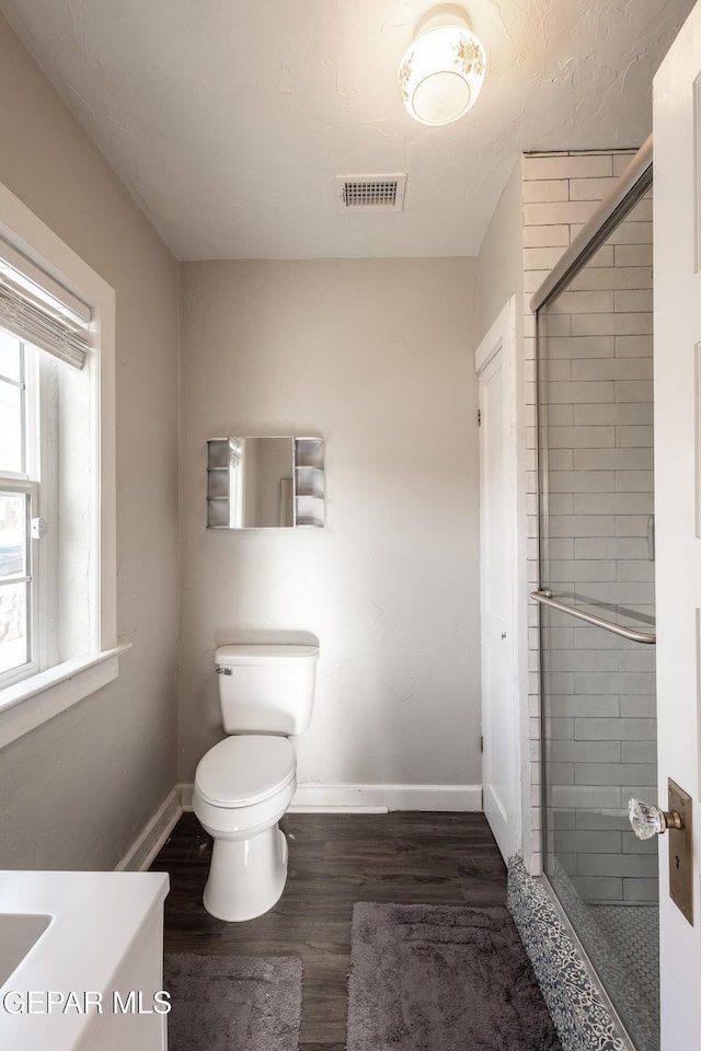 bathroom featuring vanity, toilet, hardwood / wood-style floors, and a shower with door