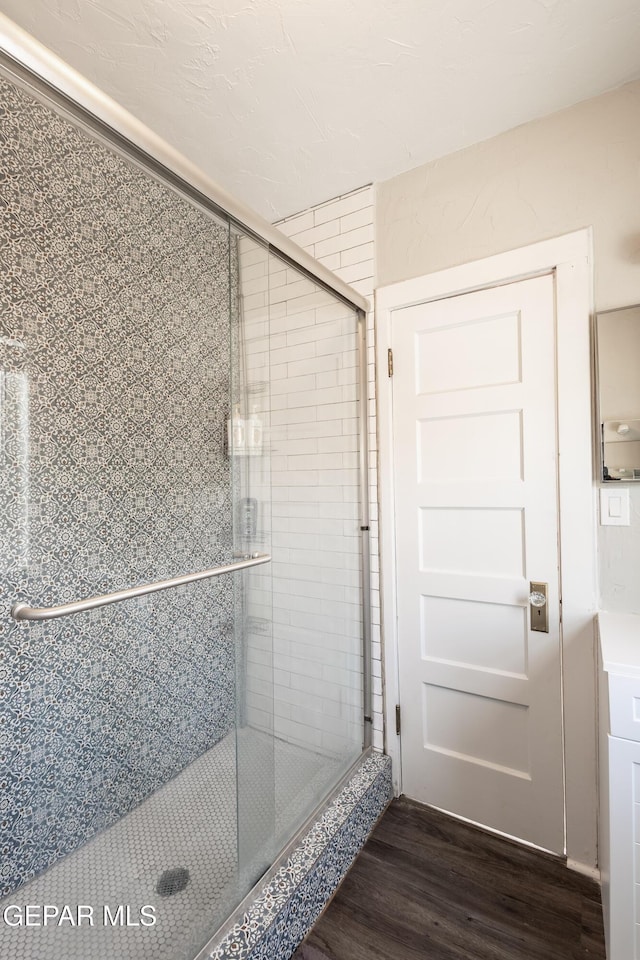 bathroom with hardwood / wood-style flooring and a shower with door