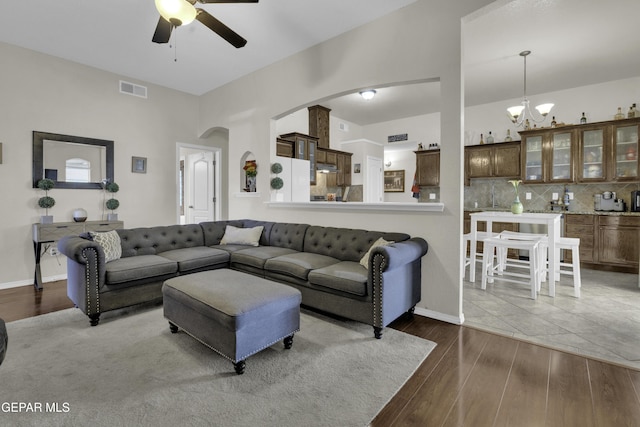 living room featuring wood-type flooring and ceiling fan with notable chandelier