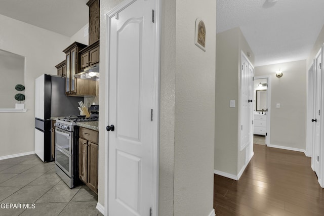 kitchen with double oven range, light stone countertops, a textured ceiling, and light wood-type flooring