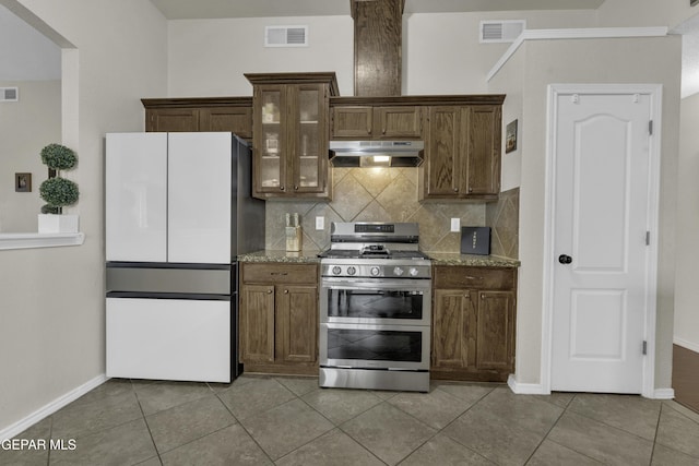 kitchen with backsplash, white refrigerator, double oven range, light tile patterned floors, and light stone counters