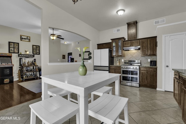 kitchen featuring light tile patterned floors, dark brown cabinets, white fridge, and range with two ovens