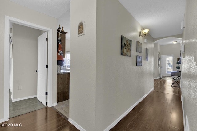 hall with a healthy amount of sunlight, dark hardwood / wood-style floors, and a textured ceiling