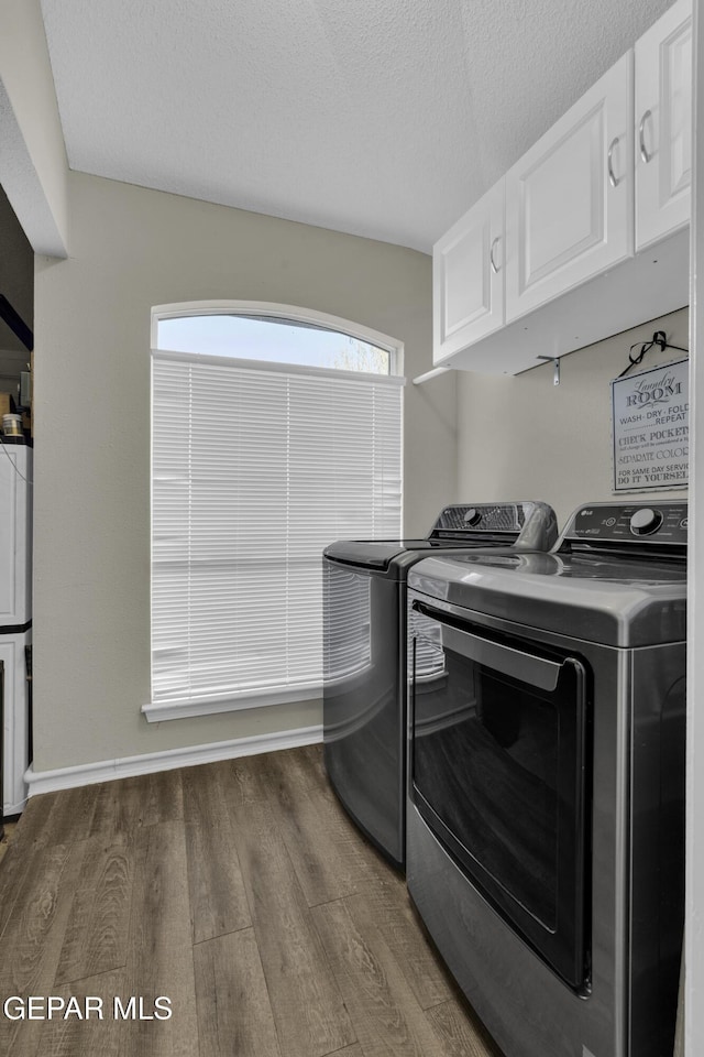 laundry area with cabinets, washer and dryer, a textured ceiling, and dark hardwood / wood-style flooring