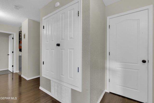 corridor with dark hardwood / wood-style floors and a textured ceiling