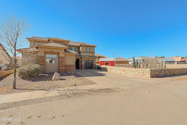 prairie-style house with stucco siding, stone siding, an attached garage, and driveway