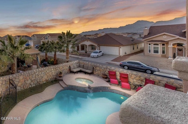 pool at dusk with an in ground hot tub