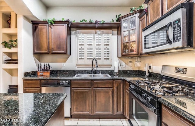 kitchen with dark stone counters, sink, light tile patterned flooring, stainless steel appliances, and dark brown cabinets