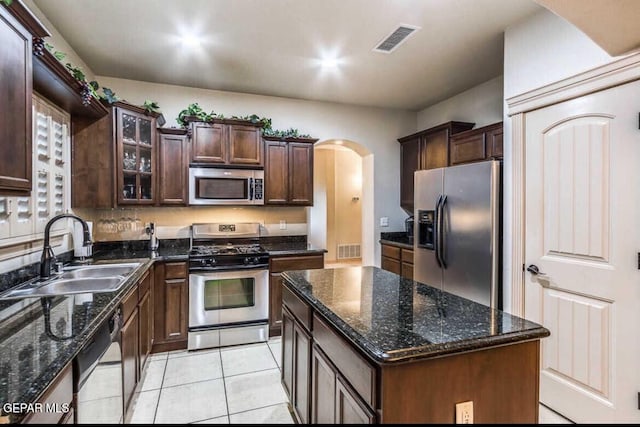 kitchen with a kitchen island, stainless steel appliances, sink, light tile patterned flooring, and dark brown cabinets