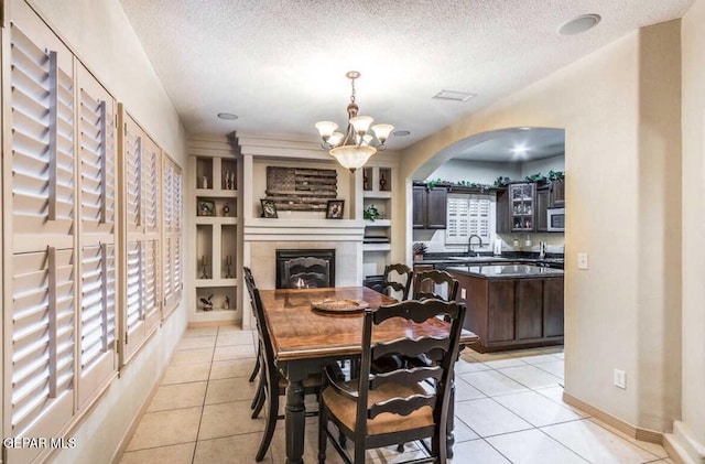 dining space with a notable chandelier, light tile patterned flooring, built in features, a textured ceiling, and sink