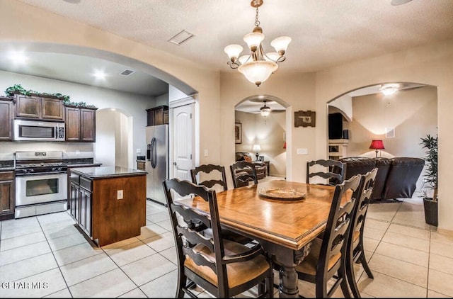 dining area featuring a textured ceiling, light tile patterned flooring, and ceiling fan with notable chandelier