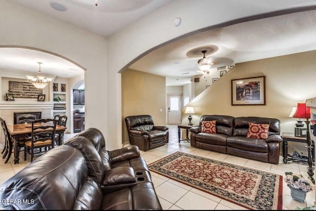 tiled living room with built in features, ceiling fan with notable chandelier, and a textured ceiling