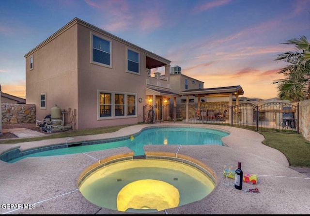 pool at dusk with an in ground hot tub