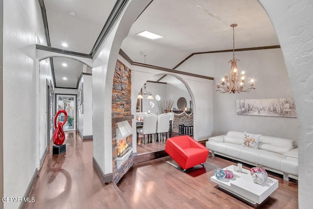 living room with lofted ceiling, wood-type flooring, crown molding, and a chandelier