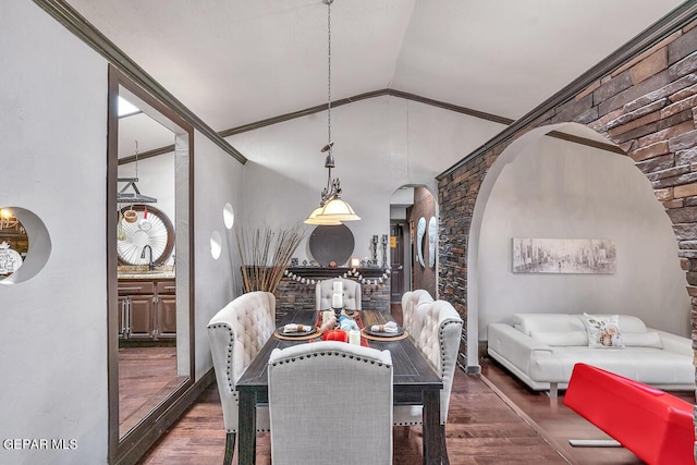 dining room with dark hardwood / wood-style floors, crown molding, and vaulted ceiling