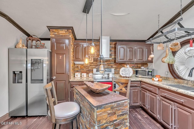 kitchen with wall chimney range hood, a kitchen island, hanging light fixtures, ornamental molding, and stainless steel appliances