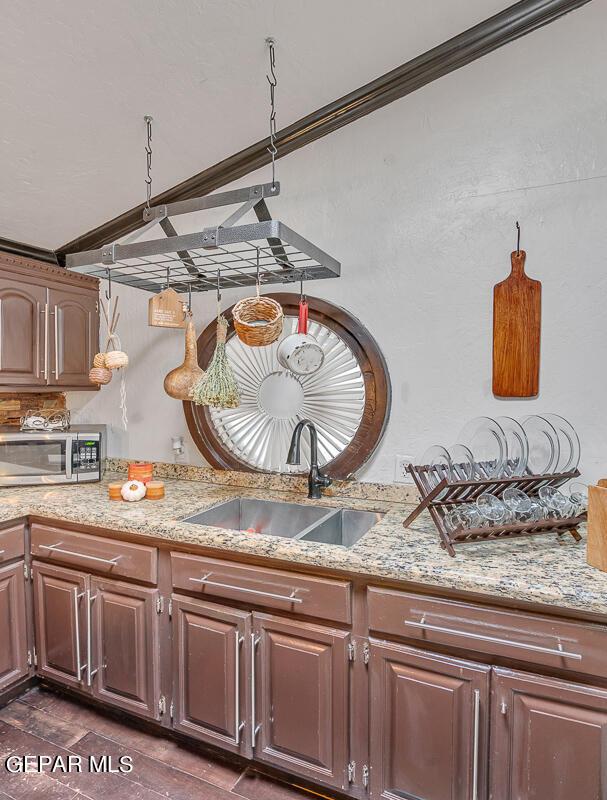 kitchen featuring ornamental molding, light stone counters, and sink