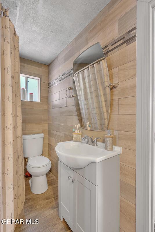 bathroom with a textured ceiling, toilet, hardwood / wood-style flooring, and vanity