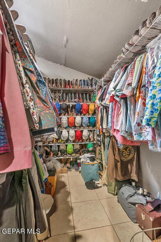 walk in closet with lofted ceiling and tile patterned floors