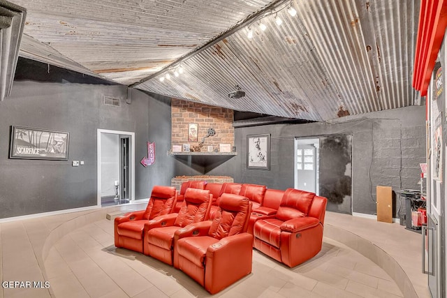 tiled home theater room featuring lofted ceiling and track lighting