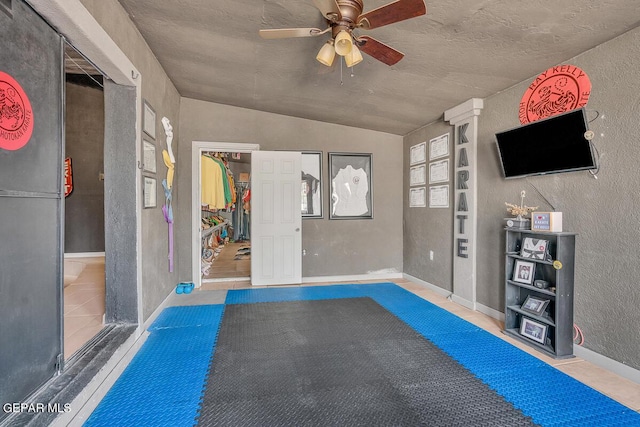 exercise area featuring ceiling fan and lofted ceiling