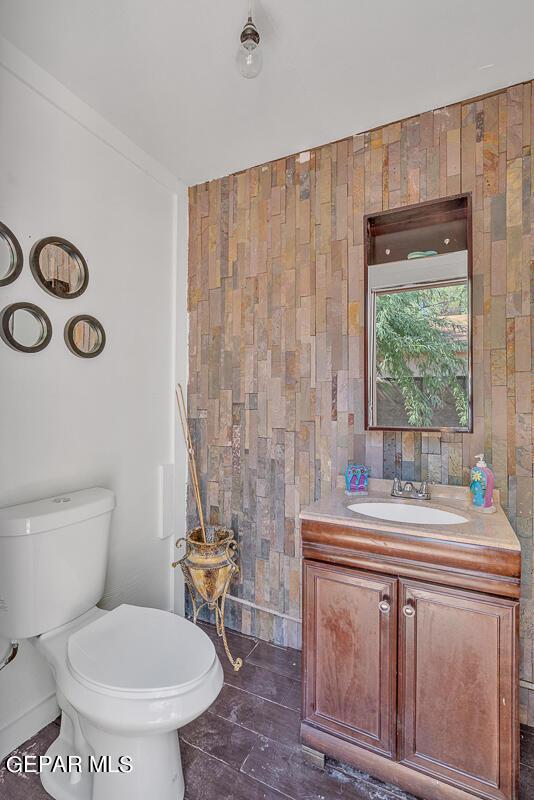 bathroom featuring toilet, tile walls, and vanity