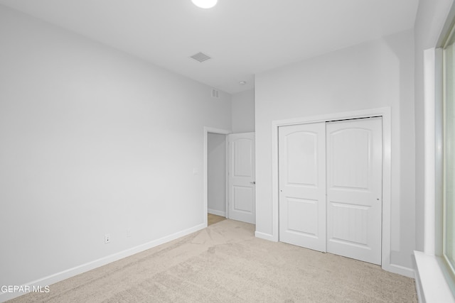 unfurnished bedroom featuring a closet and light carpet