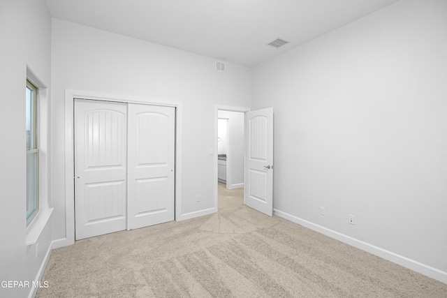 unfurnished bedroom with light carpet and a closet