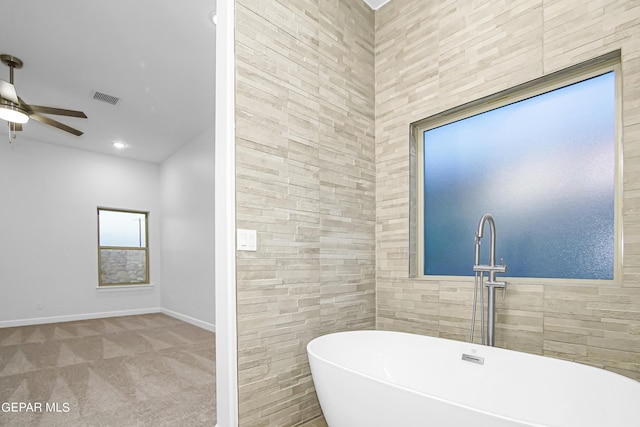 bathroom featuring a washtub, ceiling fan, and tile walls